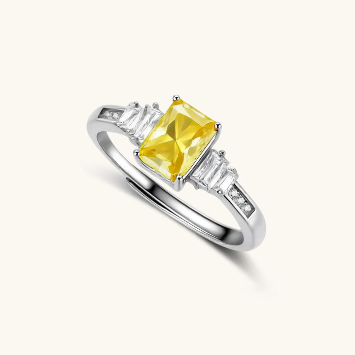 Sterling silver ring with emerald-cut yellow moissanite center stone and clear baguette side stones in elegant setting
