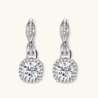Sterling silver twisted hoop earrings with round moissanite stones in halo settings against neutral background.
