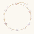 Gold vermeil chain with iridescent star-shaped baroque pearls and small round freshwater pearl drops on cream background.