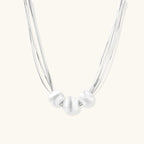 Sterling silver multi-strand necklace with three brushed round beads on cream background
