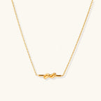 Dainty 18K gold plated necklace with infinity knot pendant on delicate chain against white background