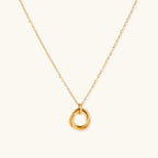 Delicate gold-plated necklace with three interlocking circle rings forming a minimalist knot pendant on cream background