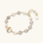 Bracelet with cloudy quartz beads, freshwater pearls, and gold-wrapped baroque pearl centerpiece on white background.