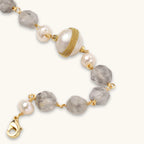Bracelet with cloudy quartz beads, freshwater pearls, and gold-wrapped baroque pearl centerpiece on white background.