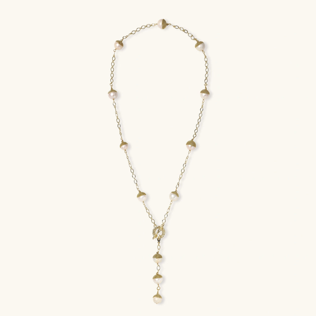 Gold-plated lariat necklace with baroque pearls and textured caps on cream background, showing adjustable Y-shaped design.