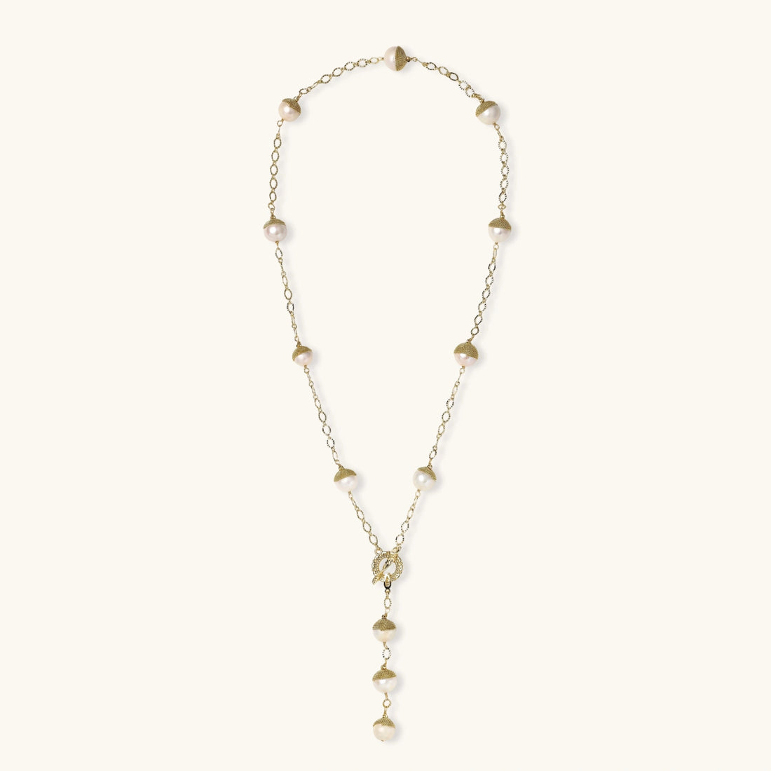 Gold-plated lariat necklace with baroque pearls and textured caps on cream background, showing adjustable Y-shaped design.