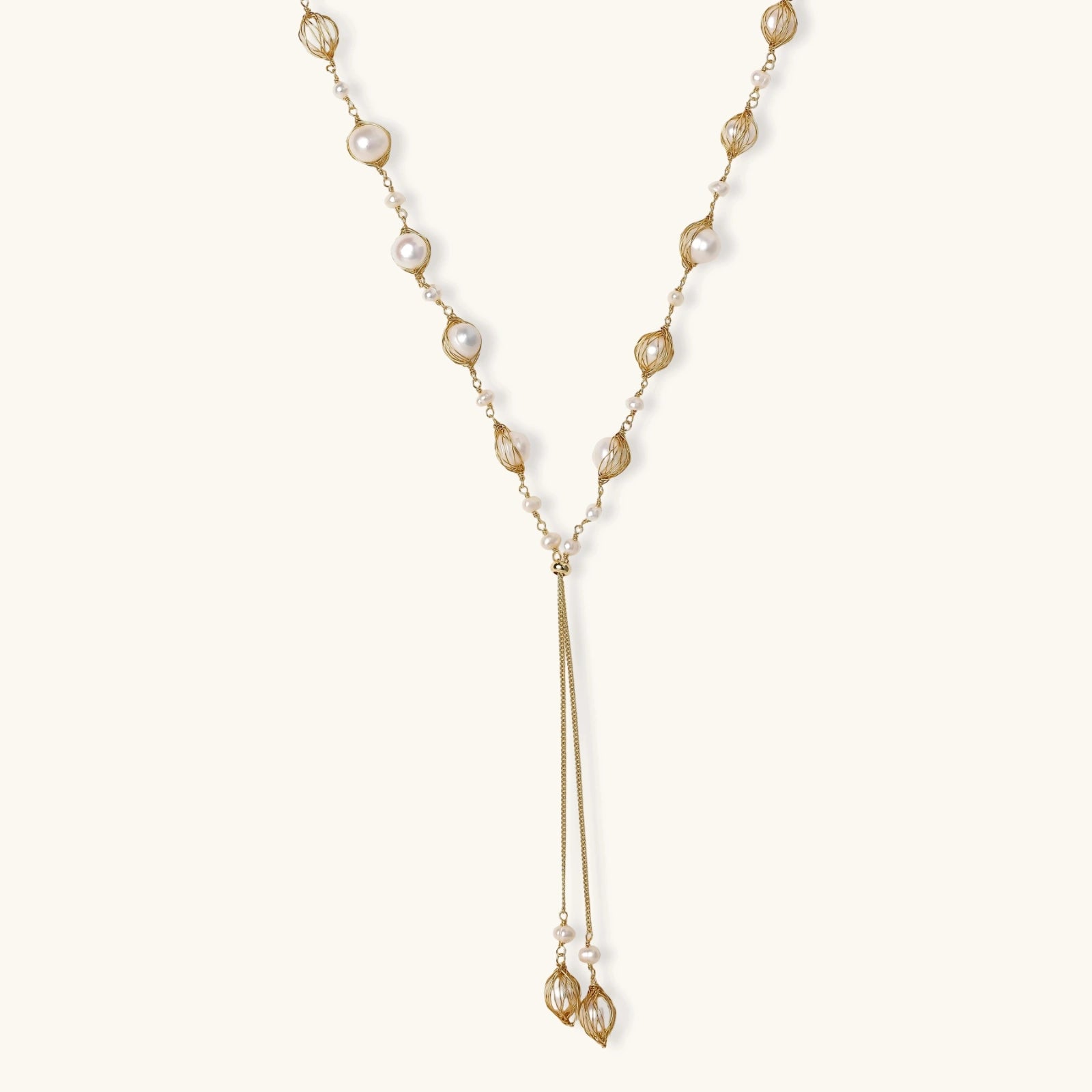 Adjustable gold lariat necklace with freshwater pearls nested in delicate cage settings and Y-shaped tassel drop