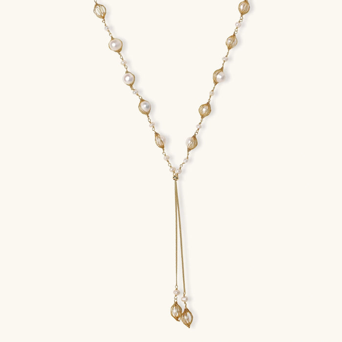 Adjustable gold lariat necklace with freshwater pearls nested in delicate cage settings and Y-shaped tassel drop