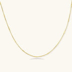 Delicate gold-plated sterling silver chain necklace with geometric segments displayed against cream background