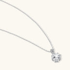 Platinum-plated sterling silver necklace with round clear crystal pendant and decorative bail on neutral background.