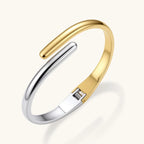Polished two-tone bypass cuff bracelet in 18K gold plated and silver stainless steel with overlapping tapered ends.