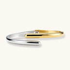 Polished two-tone bypass cuff bracelet in 18K gold plated and silver stainless steel with overlapping tapered ends.