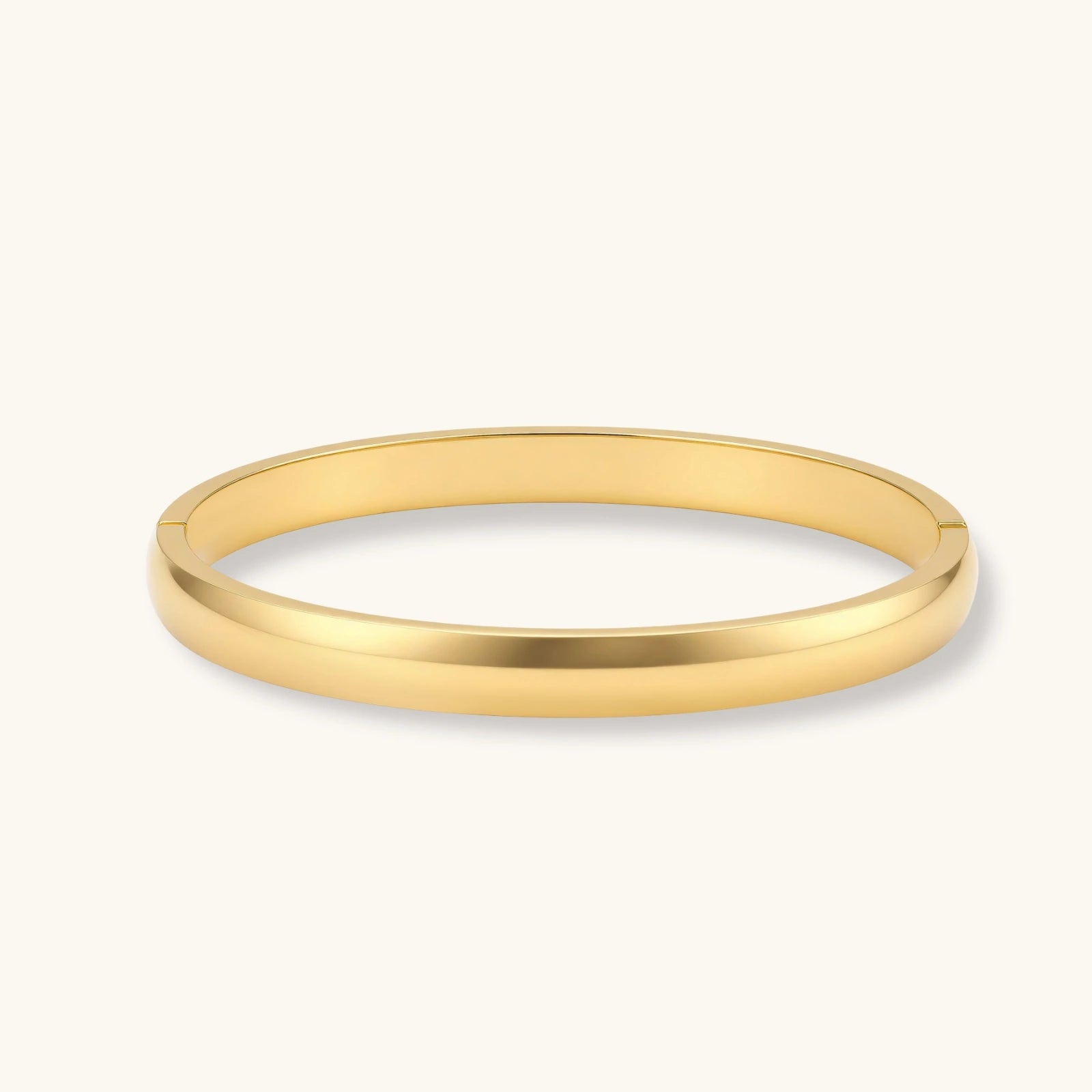 Polished 18K gold plated stainless steel hinge bangle with smooth flat-top profile on cream background.