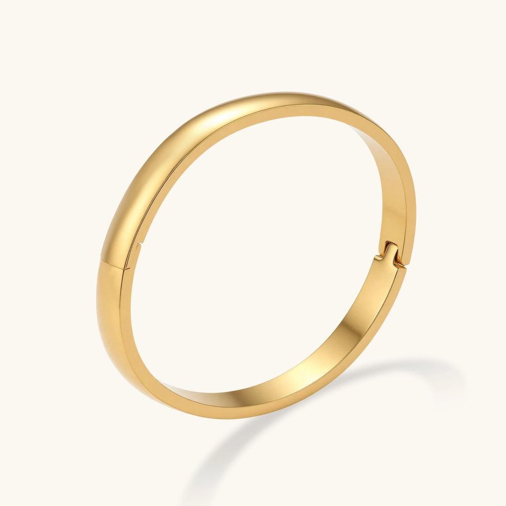 Polished 18K gold plated stainless steel hinge bangle with smooth flat-top profile on cream background.