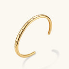 Polished 18K gold plated cuff bracelet with cubic zirconia set in star motifs on a cream background.